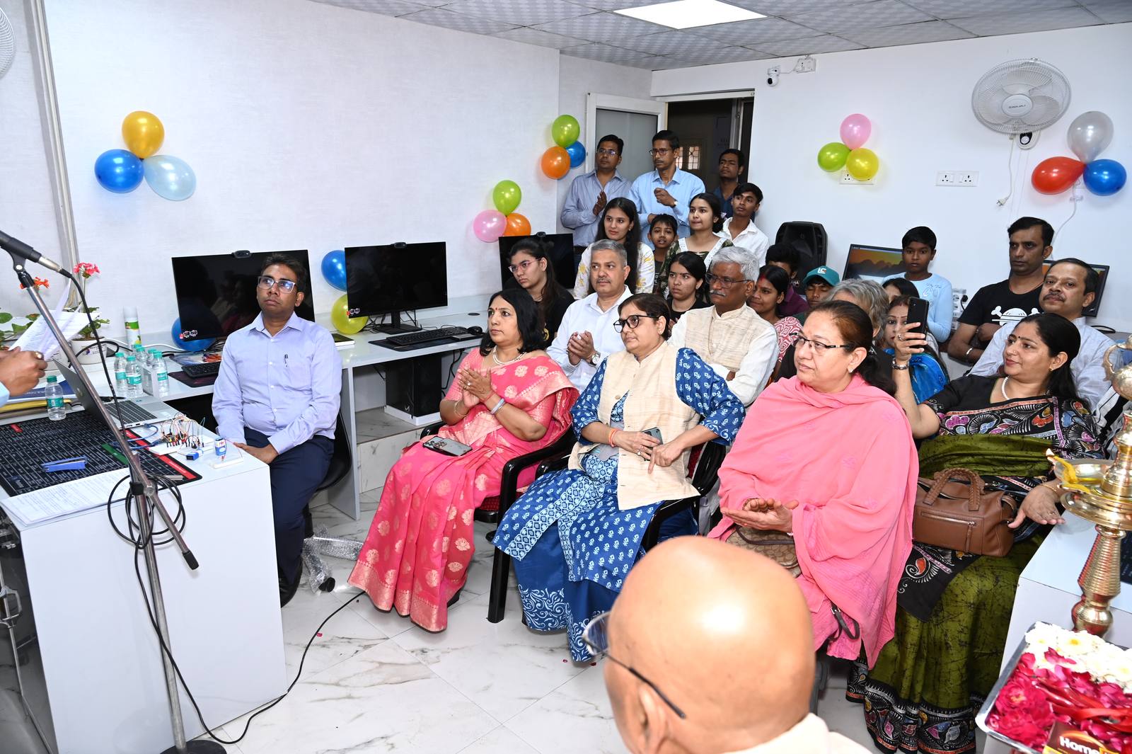 Guests and students seated in the lab, watching the presentation, with a breadboard circuit on the desk beside them.