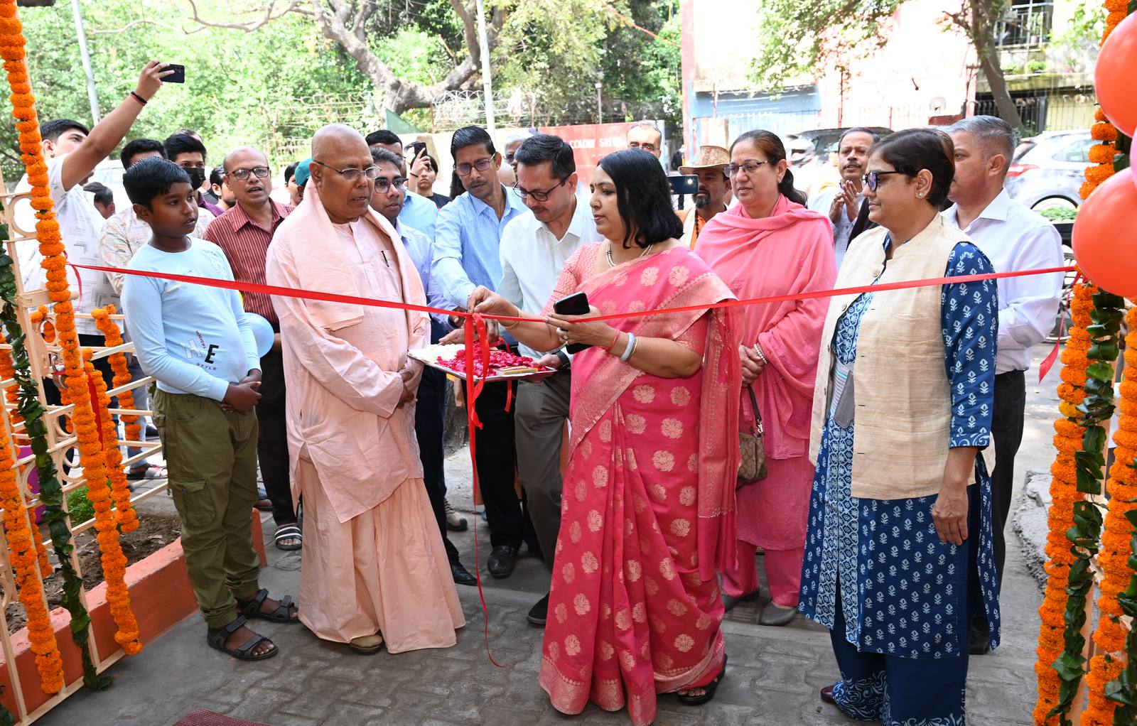 Smt. Nidhi Khare IAS cutting the ribbon at the lab entrance, with Swami Atmajnanananda Ji Maharaj and other guests looking on.